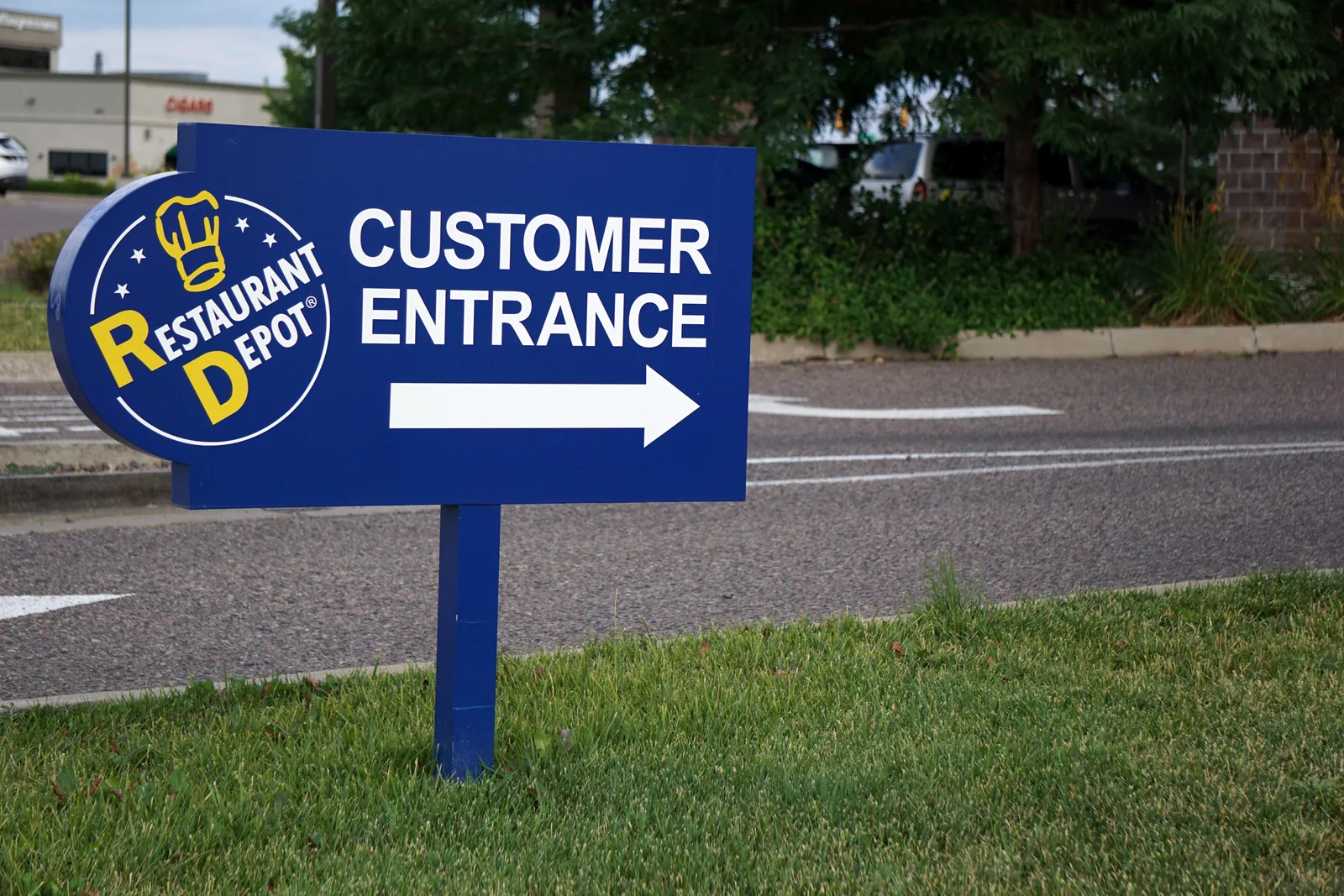 Blue directional sign for Restaurant Depot's customer entrance with arrow.