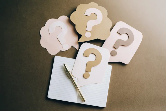 Flat lay of question mark paper crafts on a notebook, symbolizing questions and ideas. Raccogliere idee dai clienti
