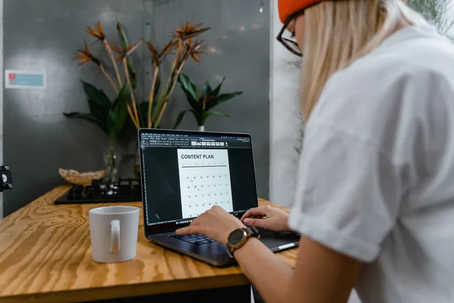 Focused woman typing on laptop while creating a content plan in a modern workspace. Rivedere contenuti e obiettivi del programma social